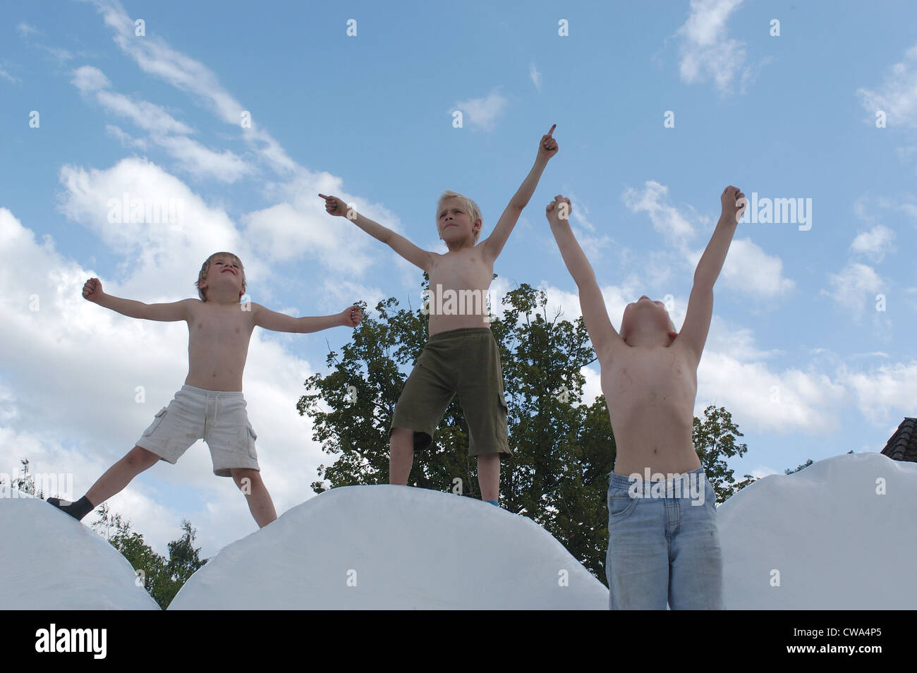 Tre ragazzi tendete le braccia verso l'alto in aria Foto Stock