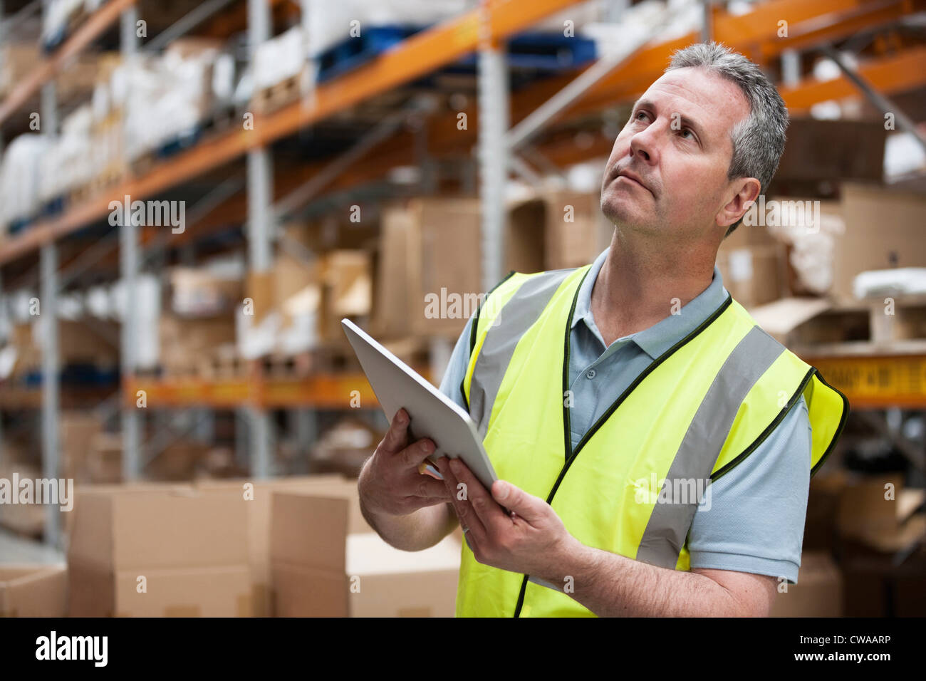 Uomo in warehouse mediante tavoletta digitale Foto Stock