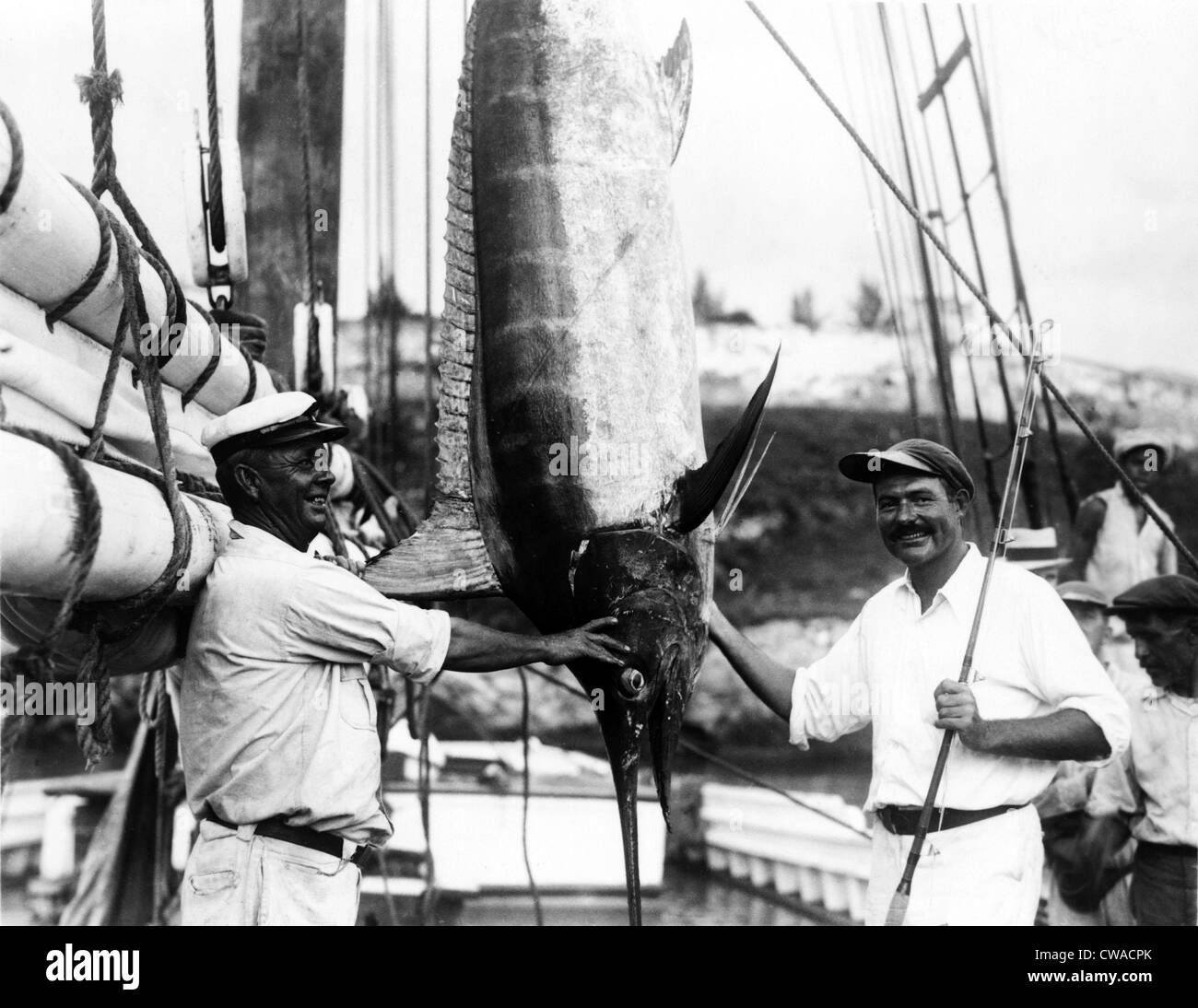 Ernest Hemingway (1899-1961), poste con il cap. Joe Russell di Key West, accanto a un enorme appeso marlin essi catturati al largo Foto Stock
