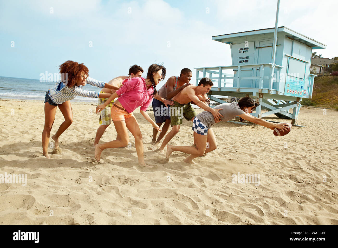 Gli amici sulla spiaggia giocando a rugby Foto Stock