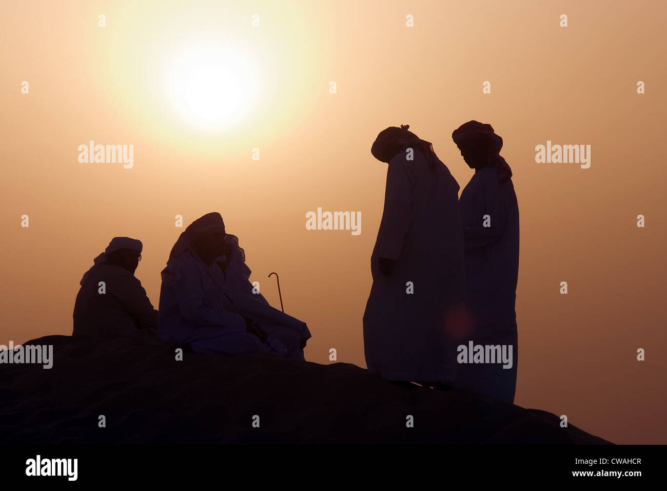 Dubai, uomini arabi nel deserto al tramonto Foto Stock
