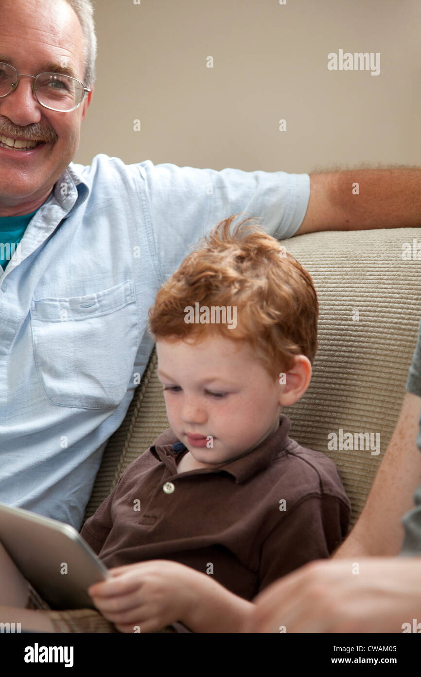 Ragazzo che guarda a tavoletta digitale con il nonno Foto Stock