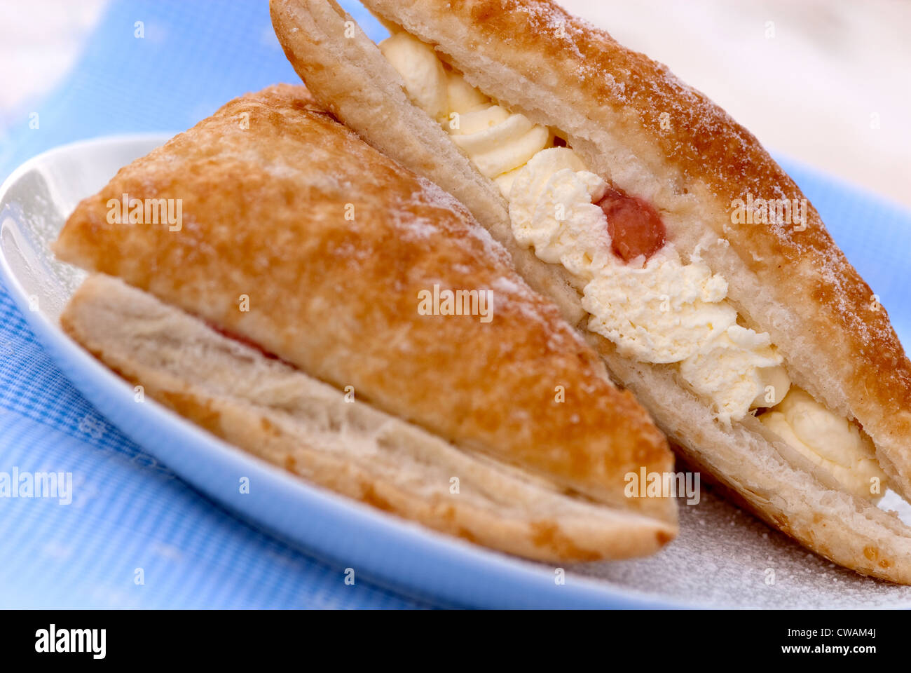 La crema bun contro un gingham blu sullo sfondo Foto Stock