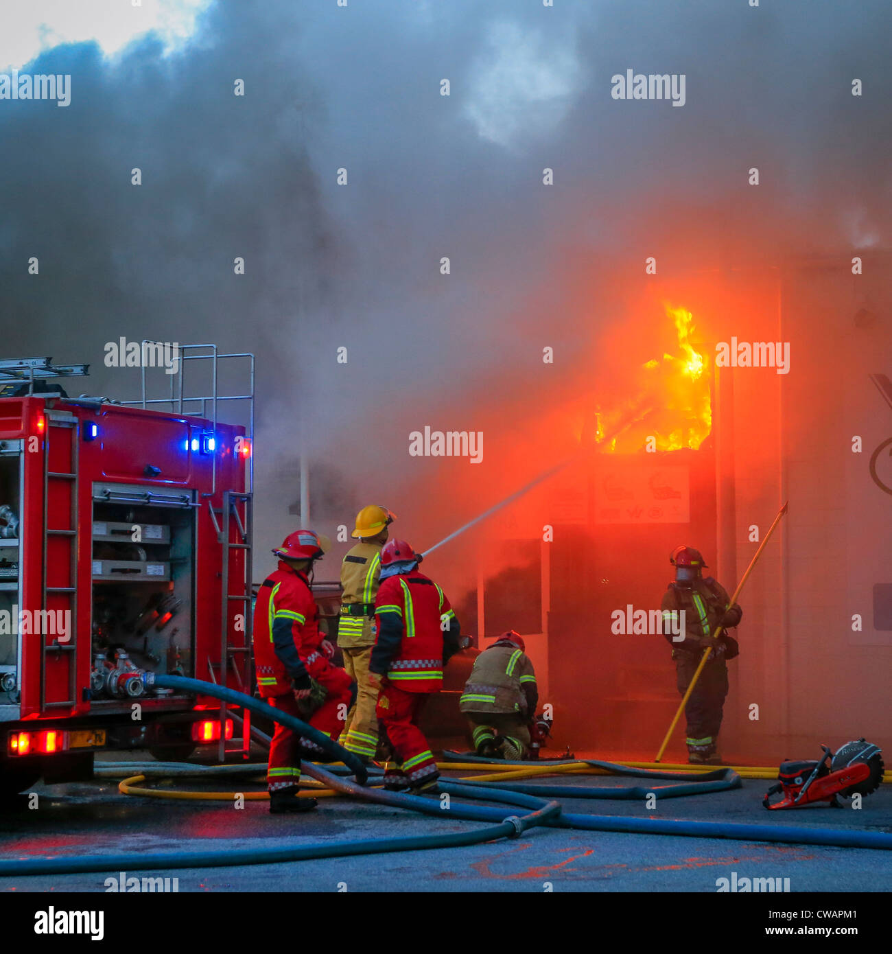 I Vigili del Fuoco in azione la spruzzatura di fiamme.Riparazione Auto negozio il fuoco nel sobborgo di Reykjavik, Islanda Foto Stock