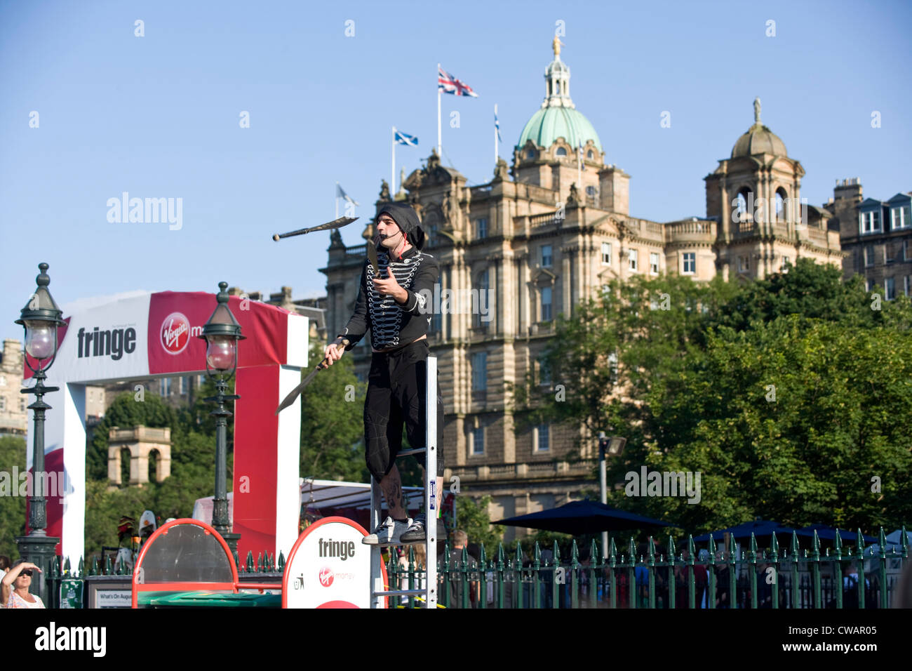 Una frangia di Edinburgh suonatore ambulante di strada giocoleria di fronte alla Bank of Scotland. Foto Stock