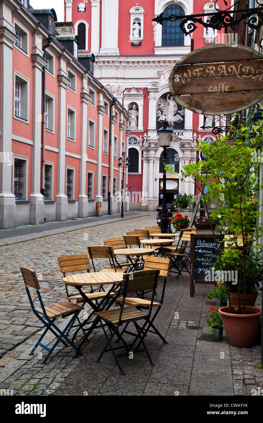 I tavoli fuori un cafe in una strada laterale fuori dalla piazza del mercato, Stary Rynek, a Poznan, in Polonia con la Fara chiesa alla fine. Foto Stock