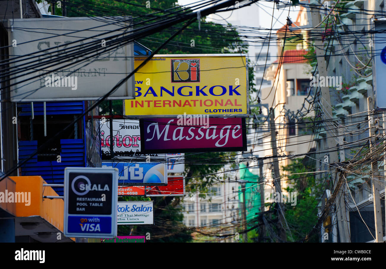 Massaggio di Bangkok e altri segni off Sukhumvit Road, Bangkok in Thailandia, tra cavi elettrici e telefonici. Foto Stock
