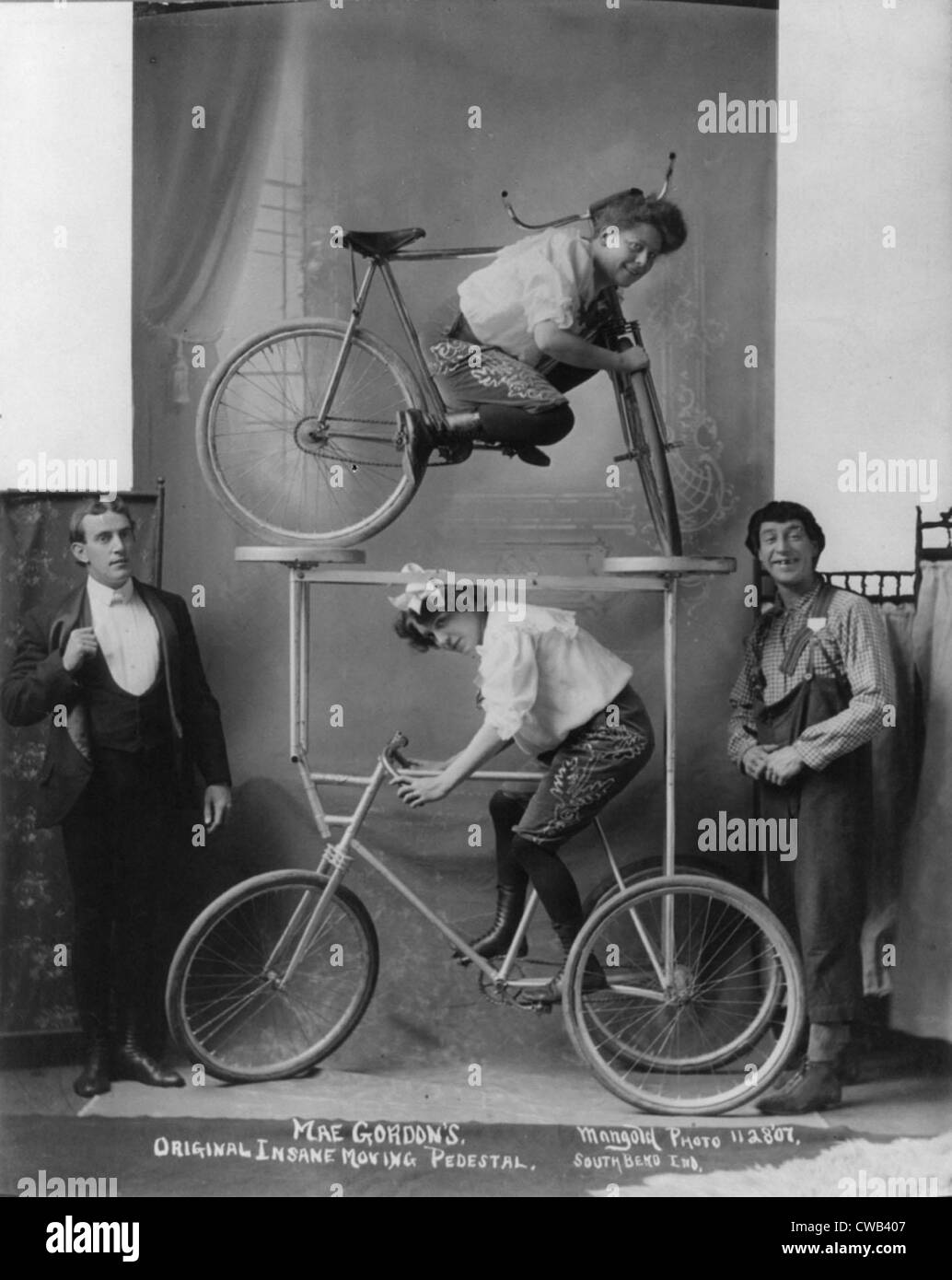 Circo e vaudeville atti, una donna tra le sbarre della bicicletta su piattaforma su triciclo, didascalia: 'Mae Gordon's pazzo originale Foto Stock