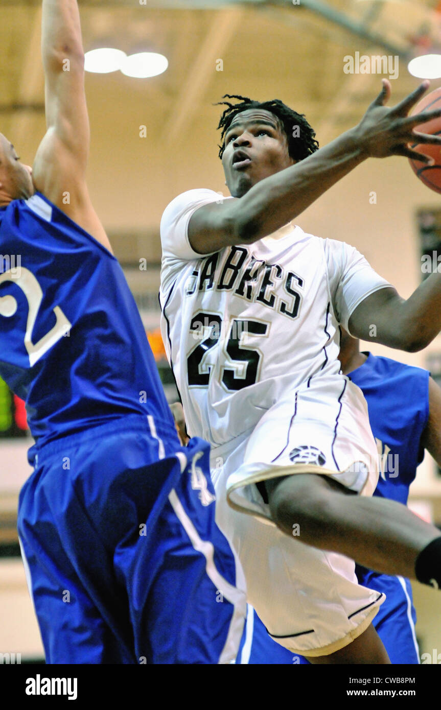 La pallacanestro di alta scuola giocatore guida sul carrello come un avversario fornisce una barriera difensiva del pompaggio. Stati Uniti d'America. Foto Stock