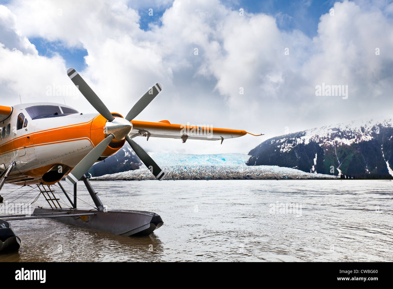 Idrovolante o float plane in Alaska che ha atterrato sull'acqua con un ghiacciaio in background. Posizione: ghiacciaio Taku Foto Stock