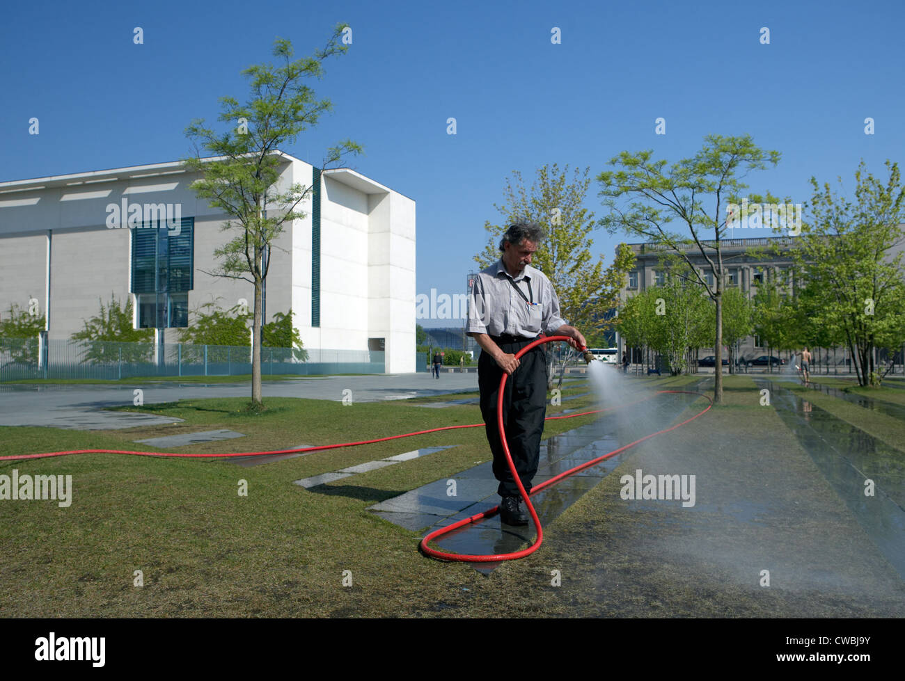 Berlino - Un uomo per irrigare il prato davanti della cancelleria Foto Stock
