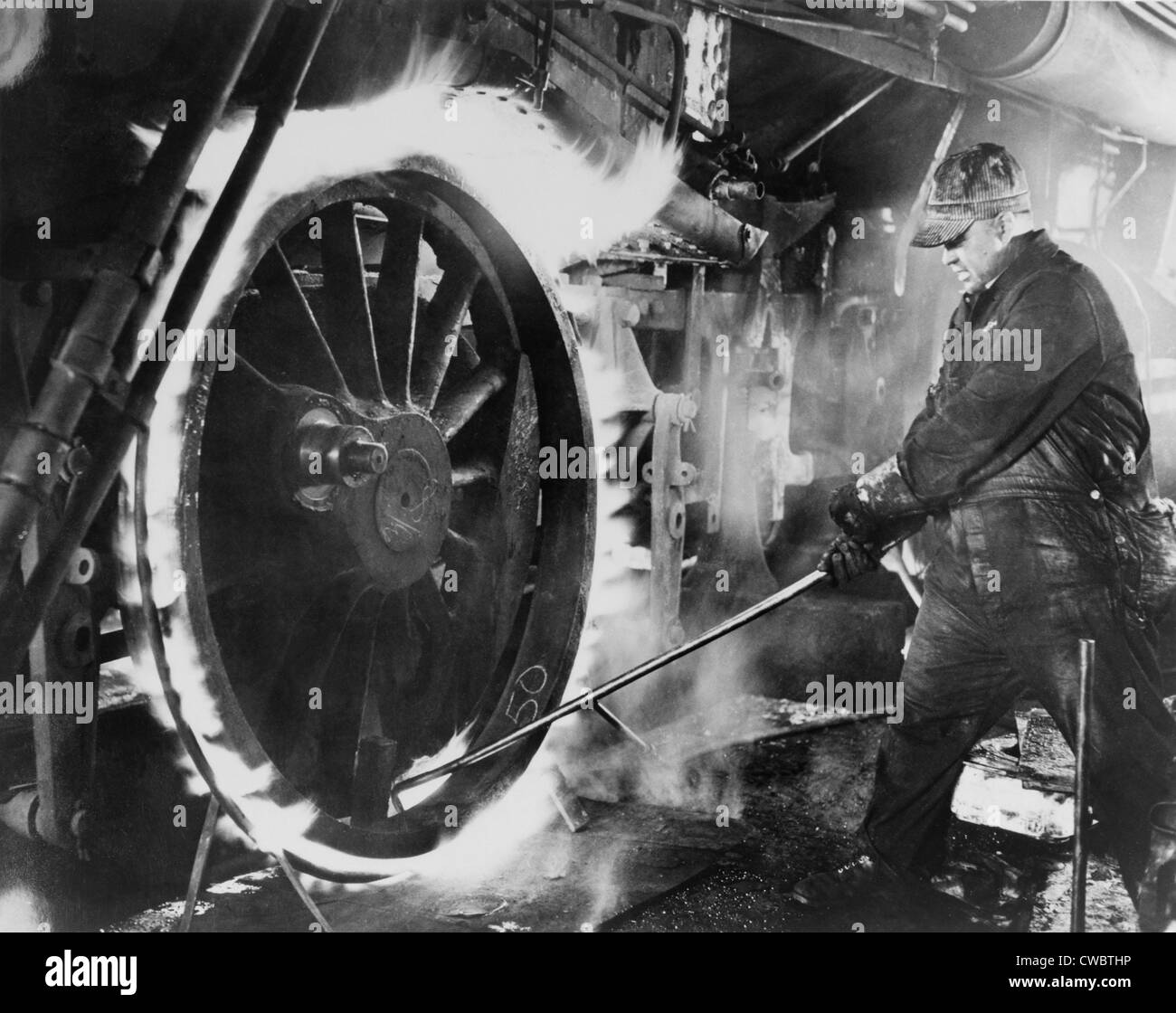 Ferrovia lavoratore sudorazione di un pneumatico sulla ruota motrice. Questo è il processo di riscaldamento del metallo circolare "pneumatico", espandere a Foto Stock