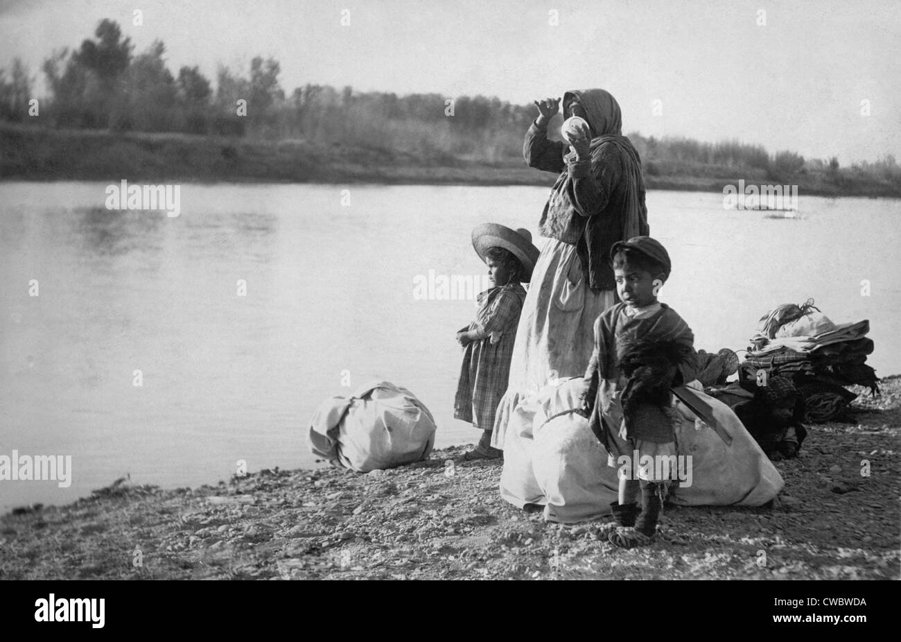 Donne messicane con i suoi figli e i pacchi sul bordo del fiume Rio Grande. Ca. 1910. Foto Stock