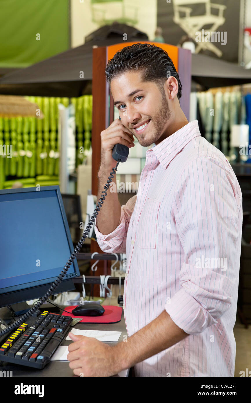 Ritratto di un addetto alle vendite felici ascoltando ricevitore telefonico in negozio Foto Stock