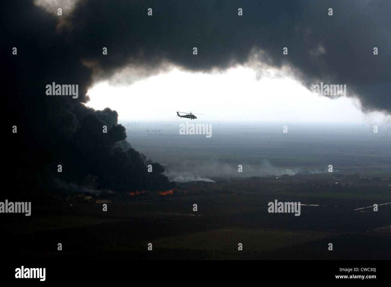 Un pennacchio di fumo che circonda una U.S. Esercito Black Hawk elicottero osservando un oleodotto fuoco fuori in avanti una base operativa Foto Stock