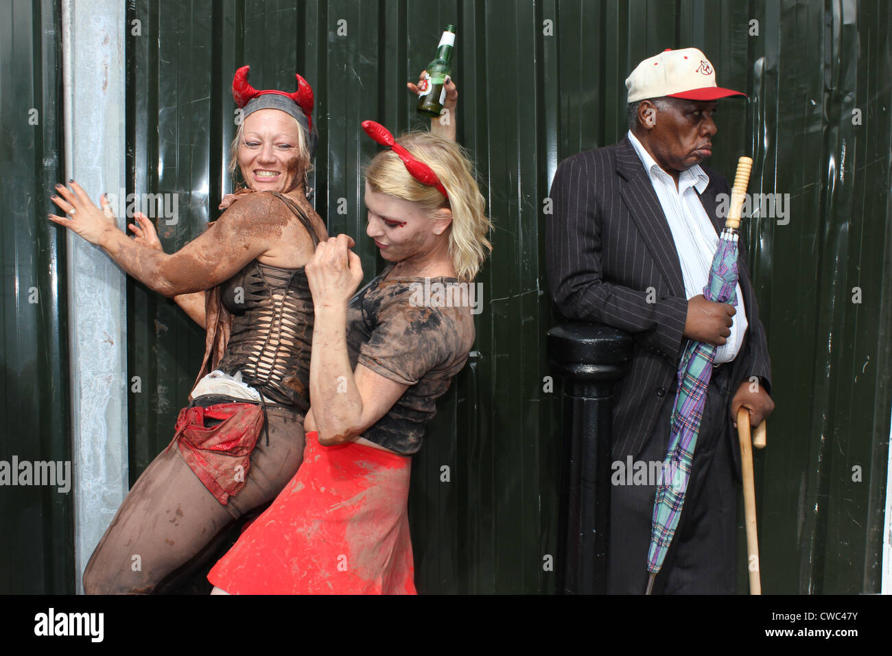 Due donne che danzano annuale al carnevale di Notting Hill con il vecchio uomo di ignorarli Foto Stock