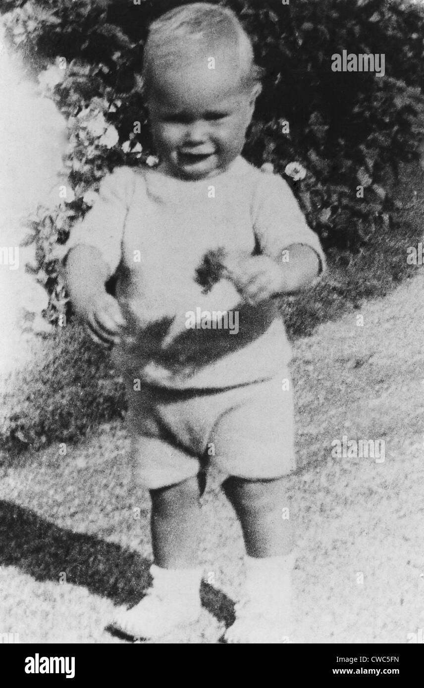 Il futuro presidente degli Stati Uniti George H.W. Bush a piedi con un fiore in mano all età di un anno e mezzo. Ca. 1925 Foto Stock