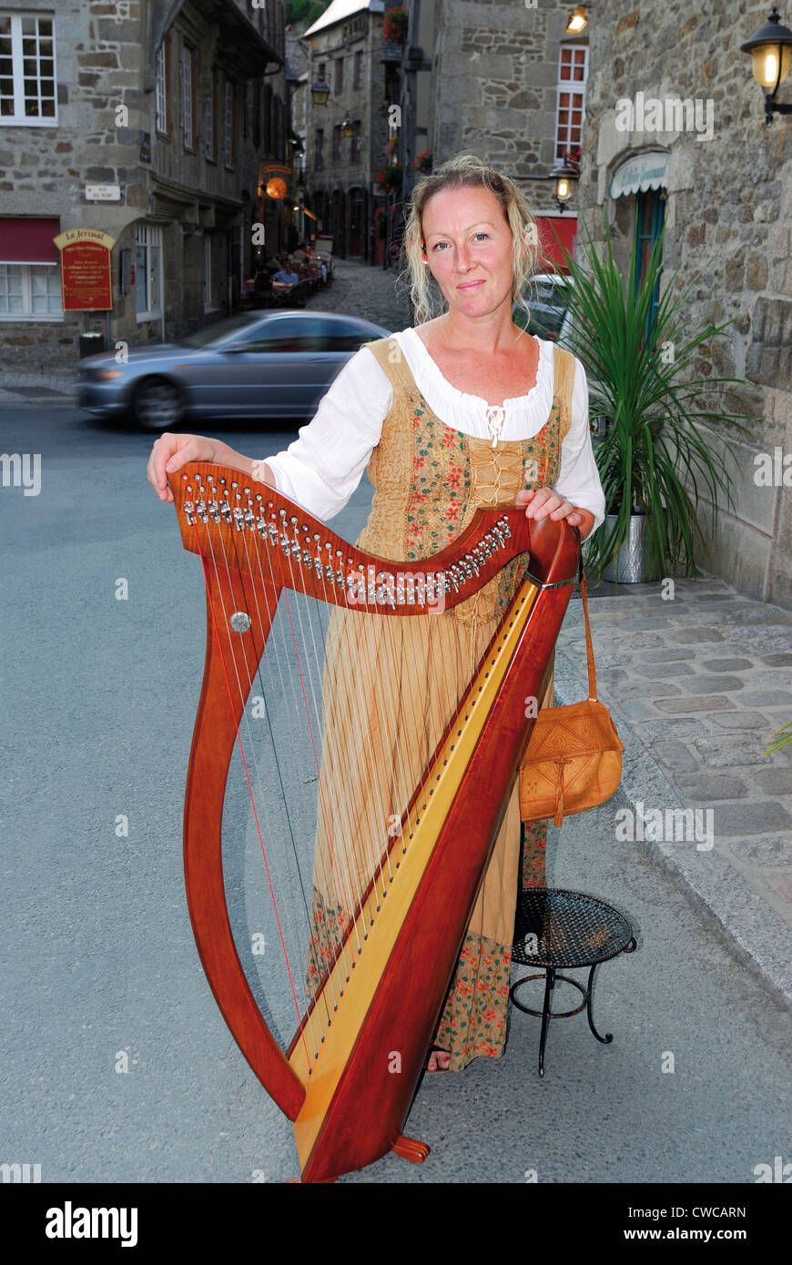 Francia, Brittany: Artista Lydwen con arpa celtica sul modo per una performance nella città medievale di Dinan Foto Stock
