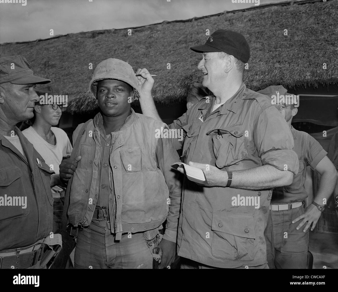 Attore John Wayne in Vietnam. John Wayne segni privato di prima classe Wofford Fonsell il casco durante la sua visita al terzo Foto Stock
