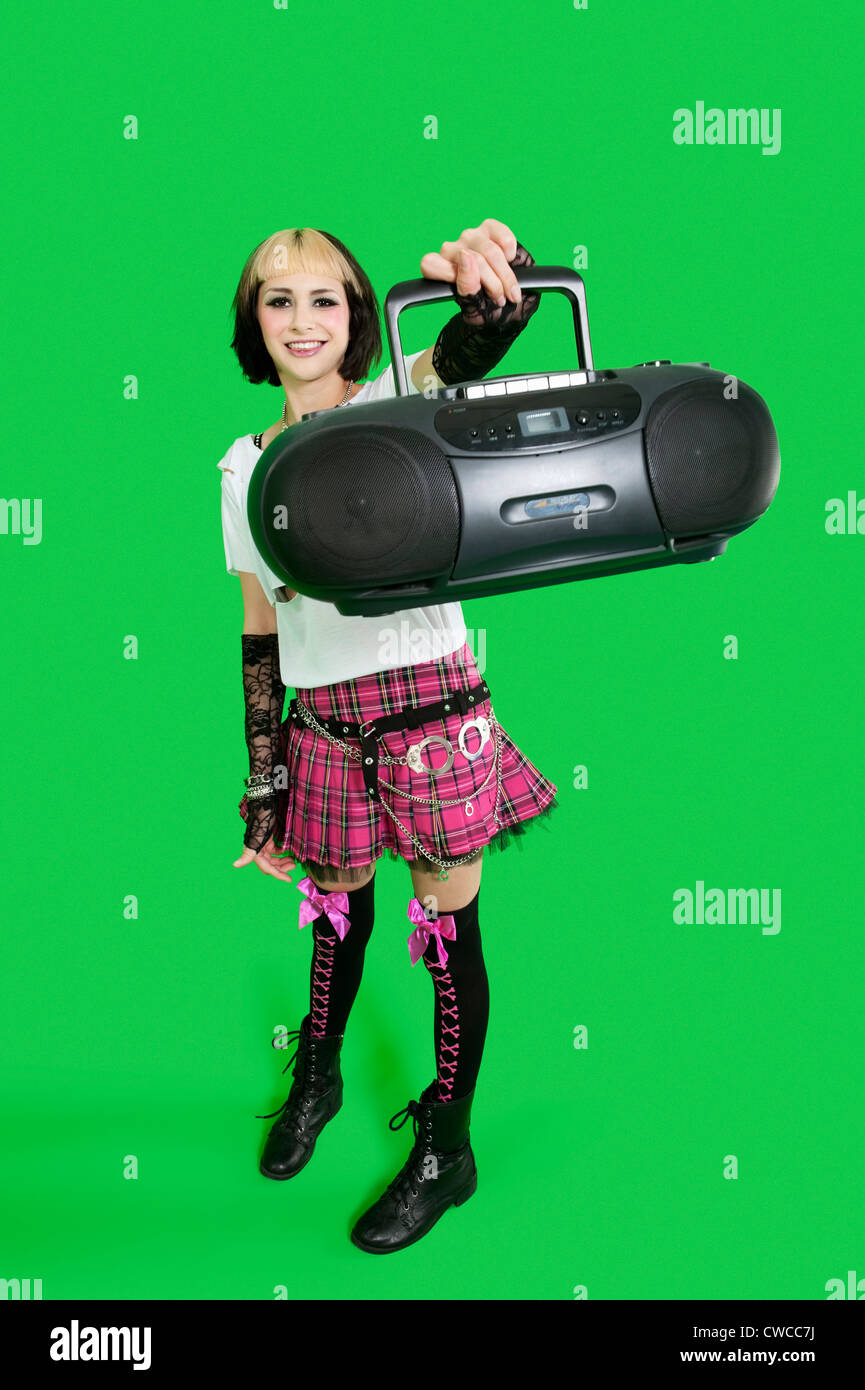 Ritratto di giovane donna azienda boom box su sfondo verde Foto Stock