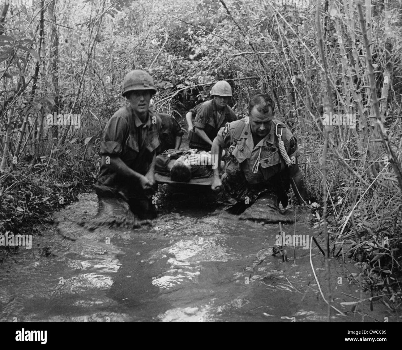 Guerra del Vietnam. I soldati USA portano un ferito il compagno attraverso una zona paludosa. 1969. Foto Stock