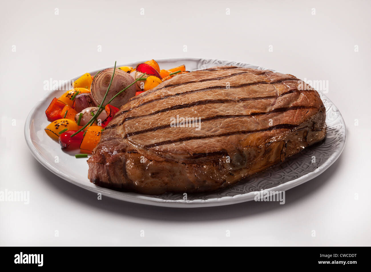 Un placcato, grigliate di nervatura-eye bistecca di manzo con scalogno andyellow e pepe rosso guarnire. Foto Stock