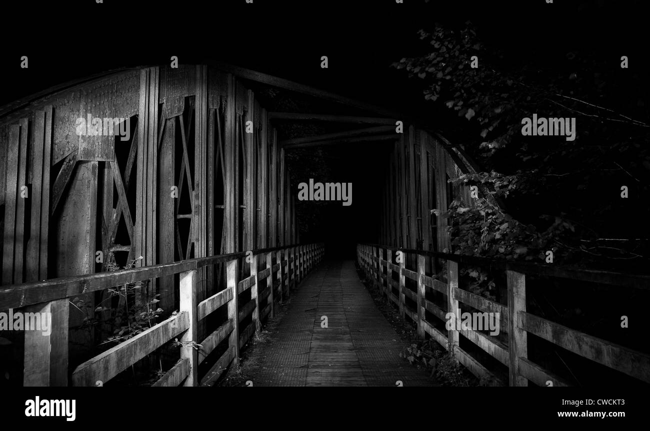 Bianco e nero abbandonato ponte ferroviario di notte illuminate da fiaccole Foto Stock