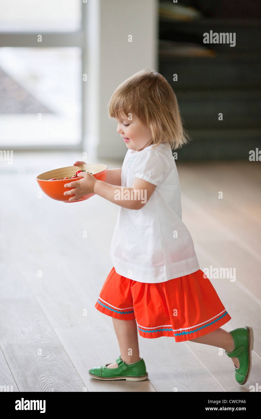 La ragazza che porta una ciotola di cibo Foto Stock