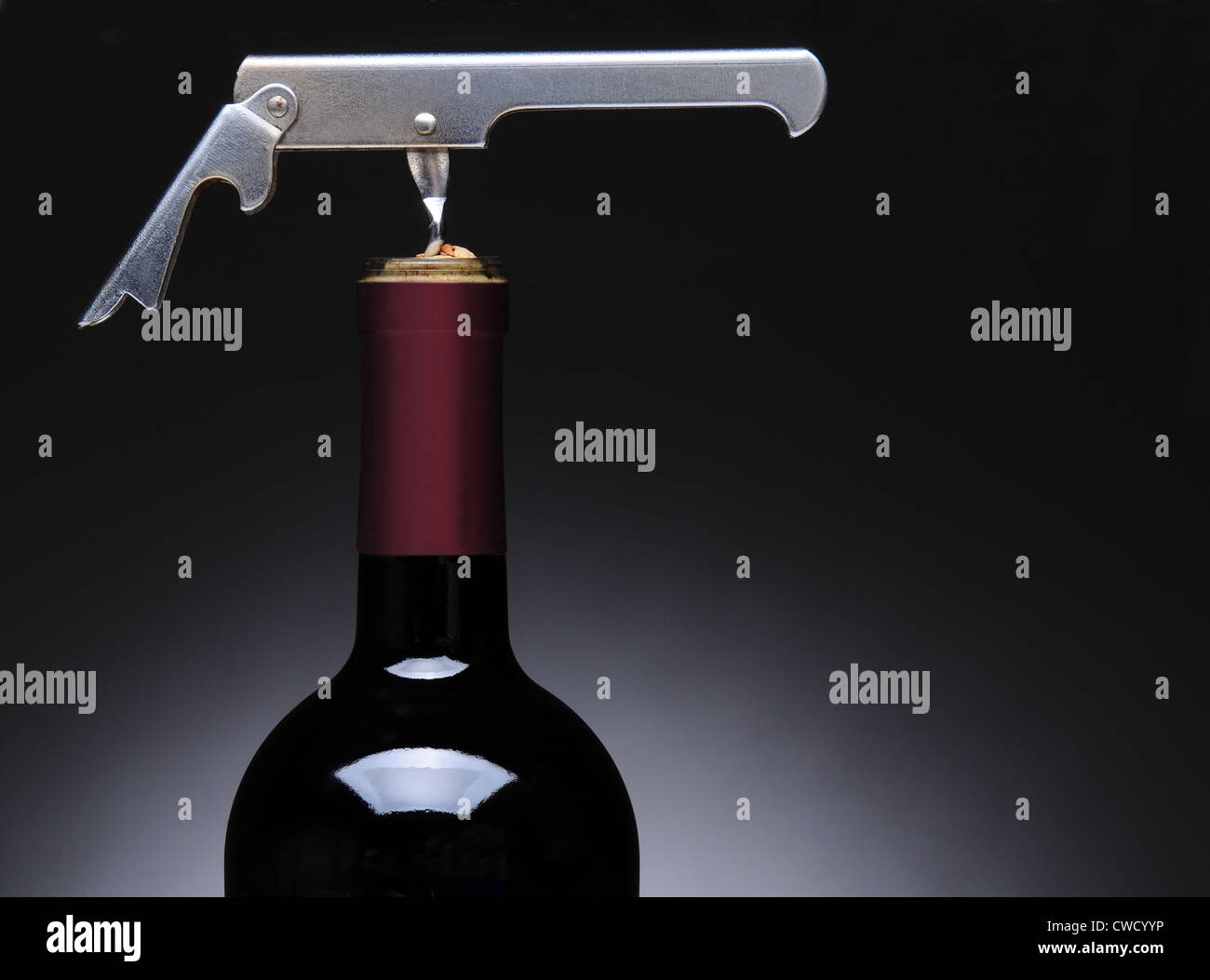 Primo piano di un metallo camerieri cavatappi in una bottiglia di vino. Formato orizzontale su una luce di sfondo grigio scuro. Foto Stock