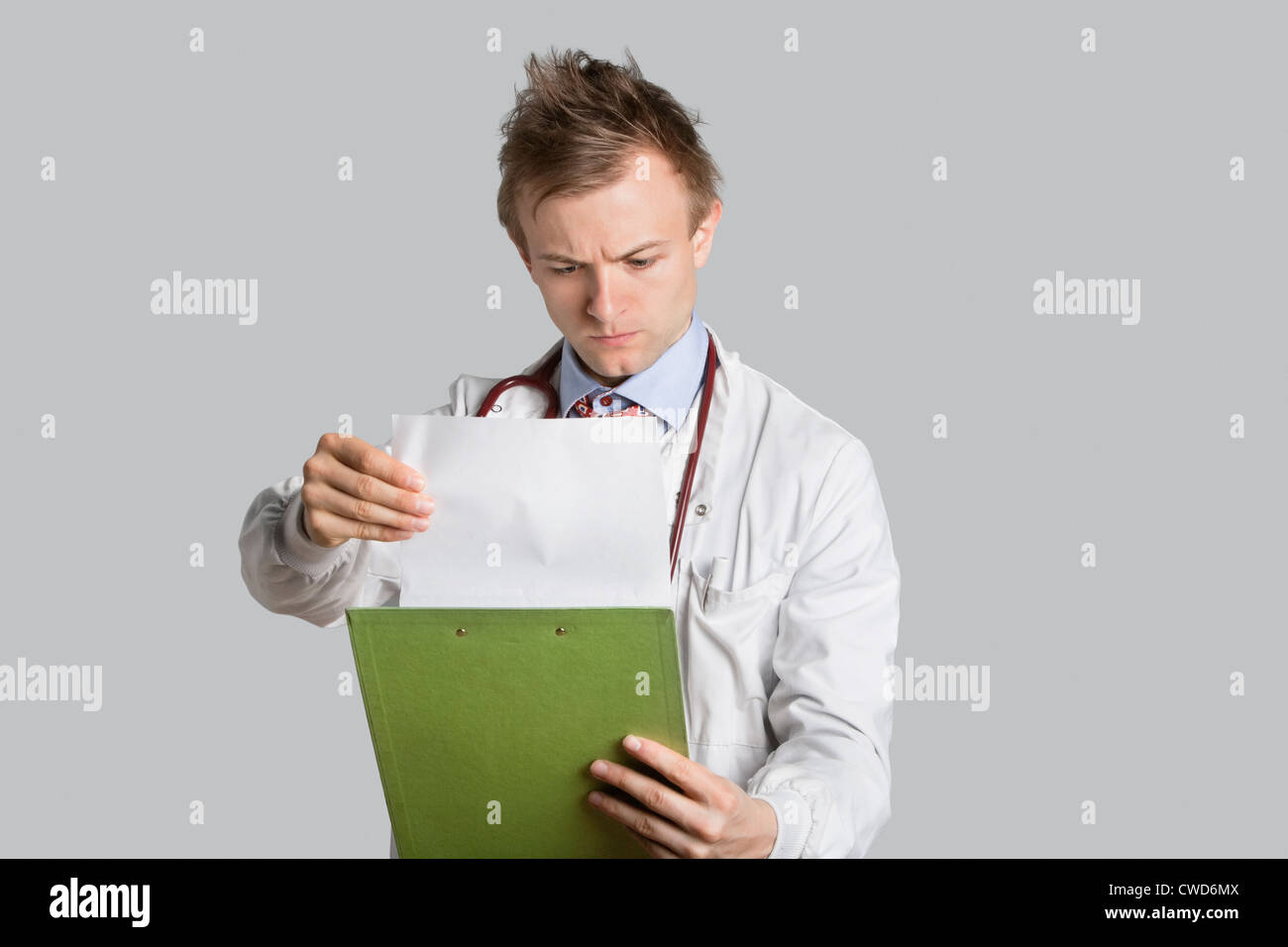 Medico di sesso maschile di lettura record medici su sfondo grigio Foto Stock