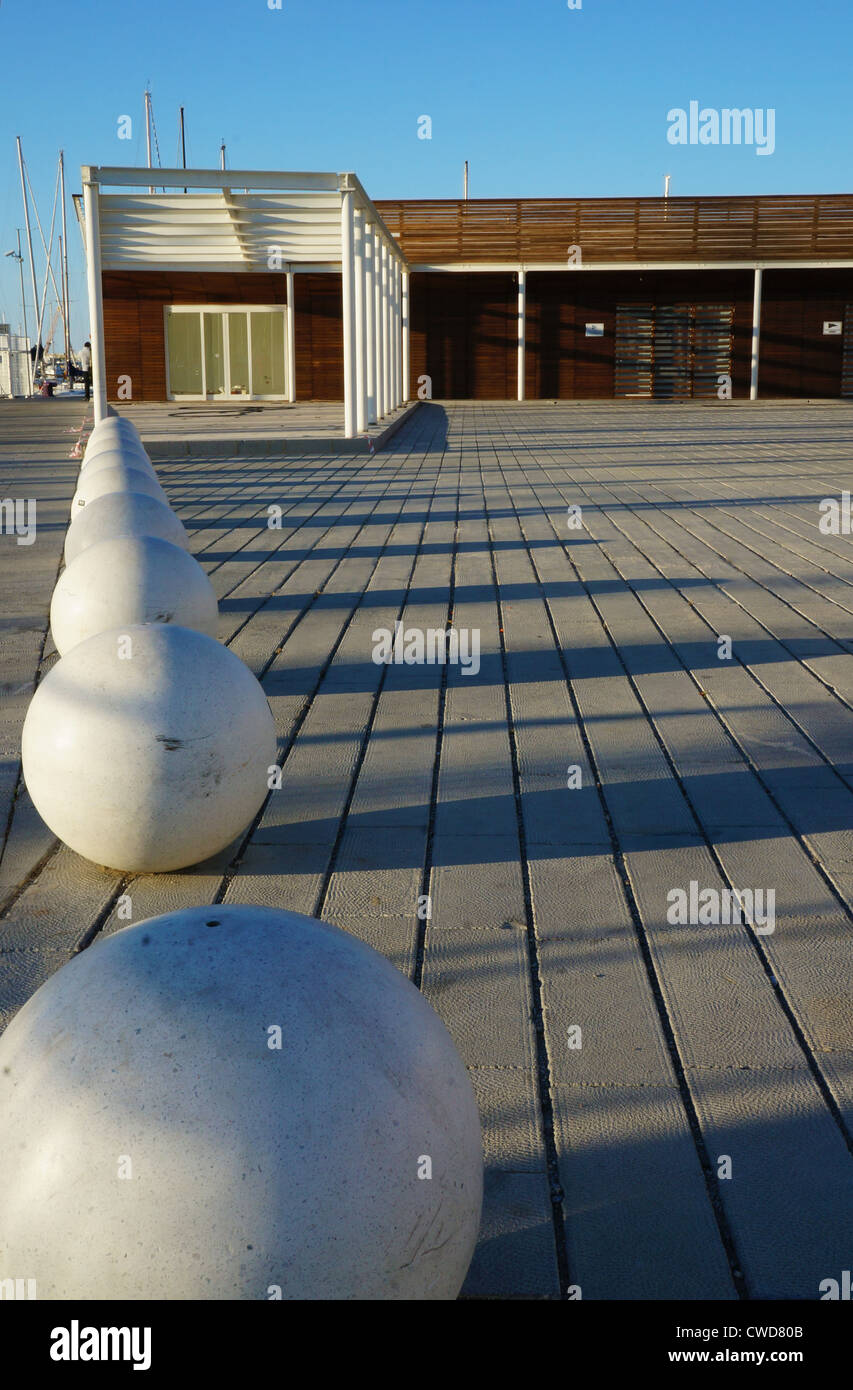 Esplanade urbano con panchine sferica e un edificio di legno in una giornata di sole Foto Stock