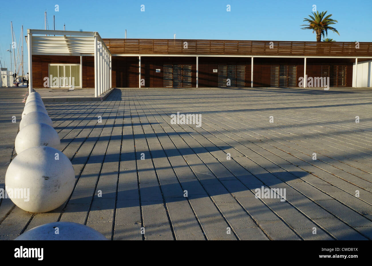 Esplanade urbano con panchine sferica e un edificio di legno in una giornata di sole Foto Stock