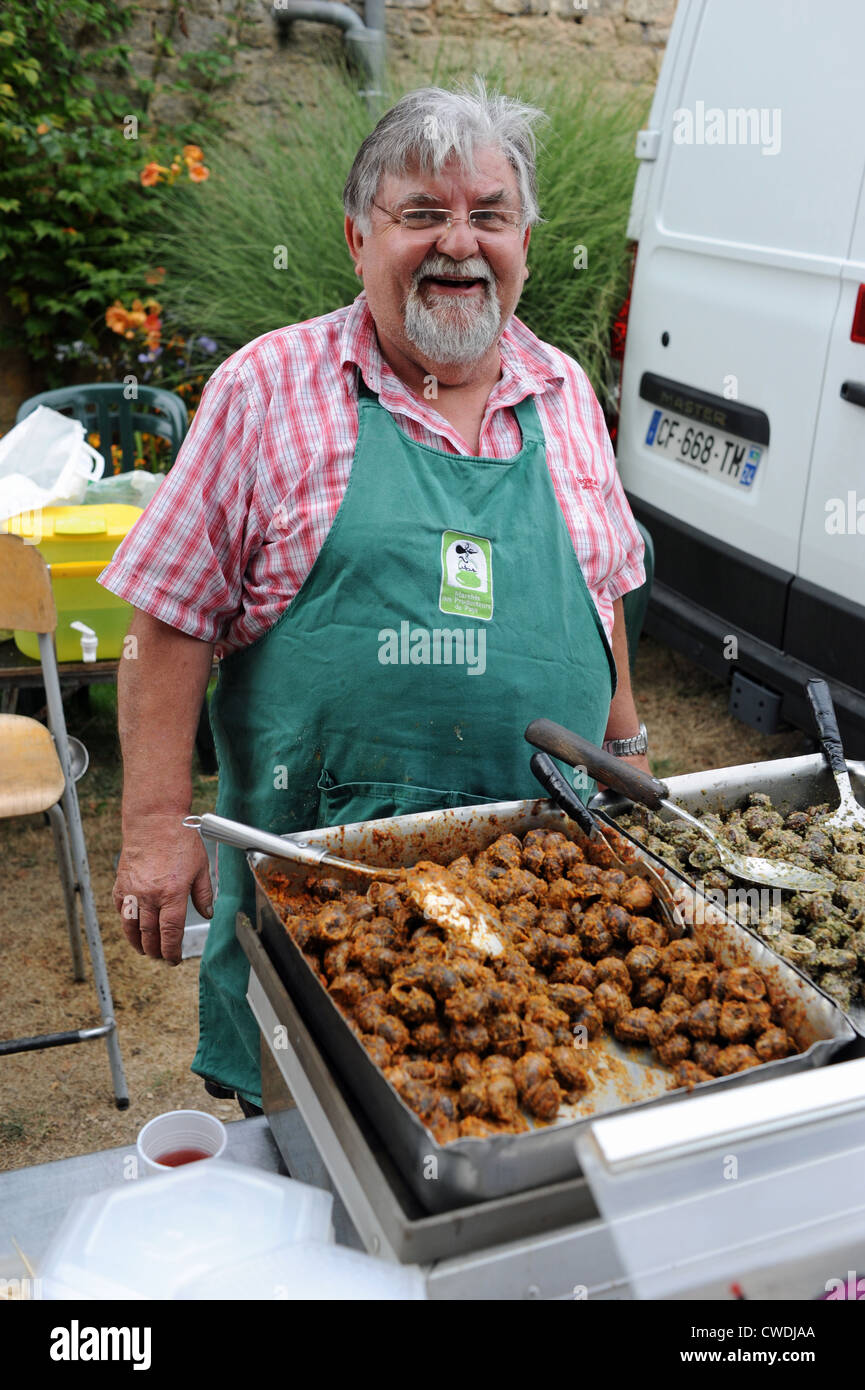 Uomo che serve le lumache al villaggio serata picnic a Loubejac nella regione della Dordogne del sud-ovest della Francia Europa Foto Stock