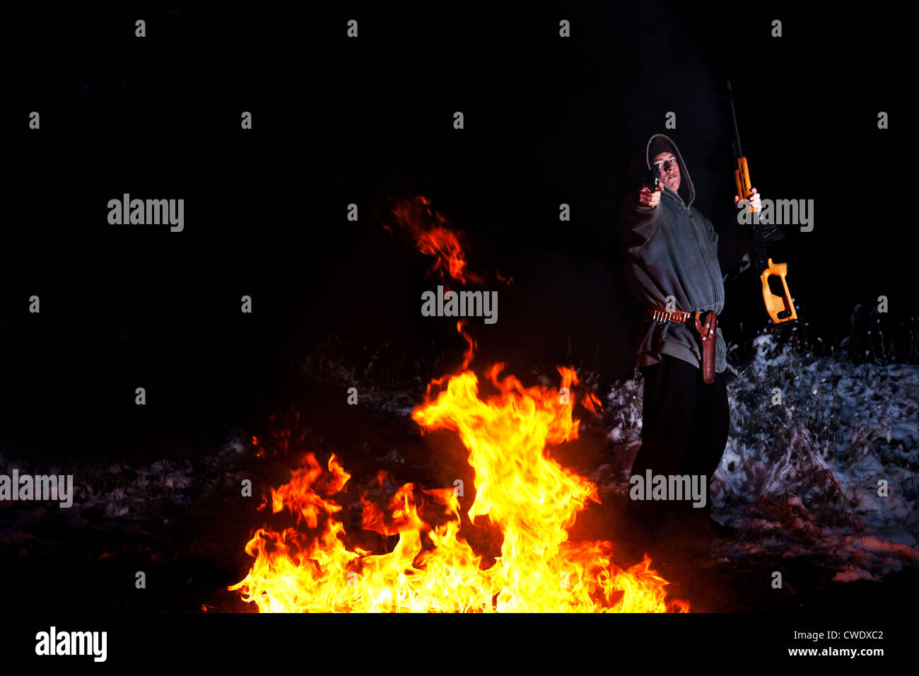 Un giovane uomo che punta una pistola alla telecamera circondati dalle fiamme nel Montana. Foto Stock