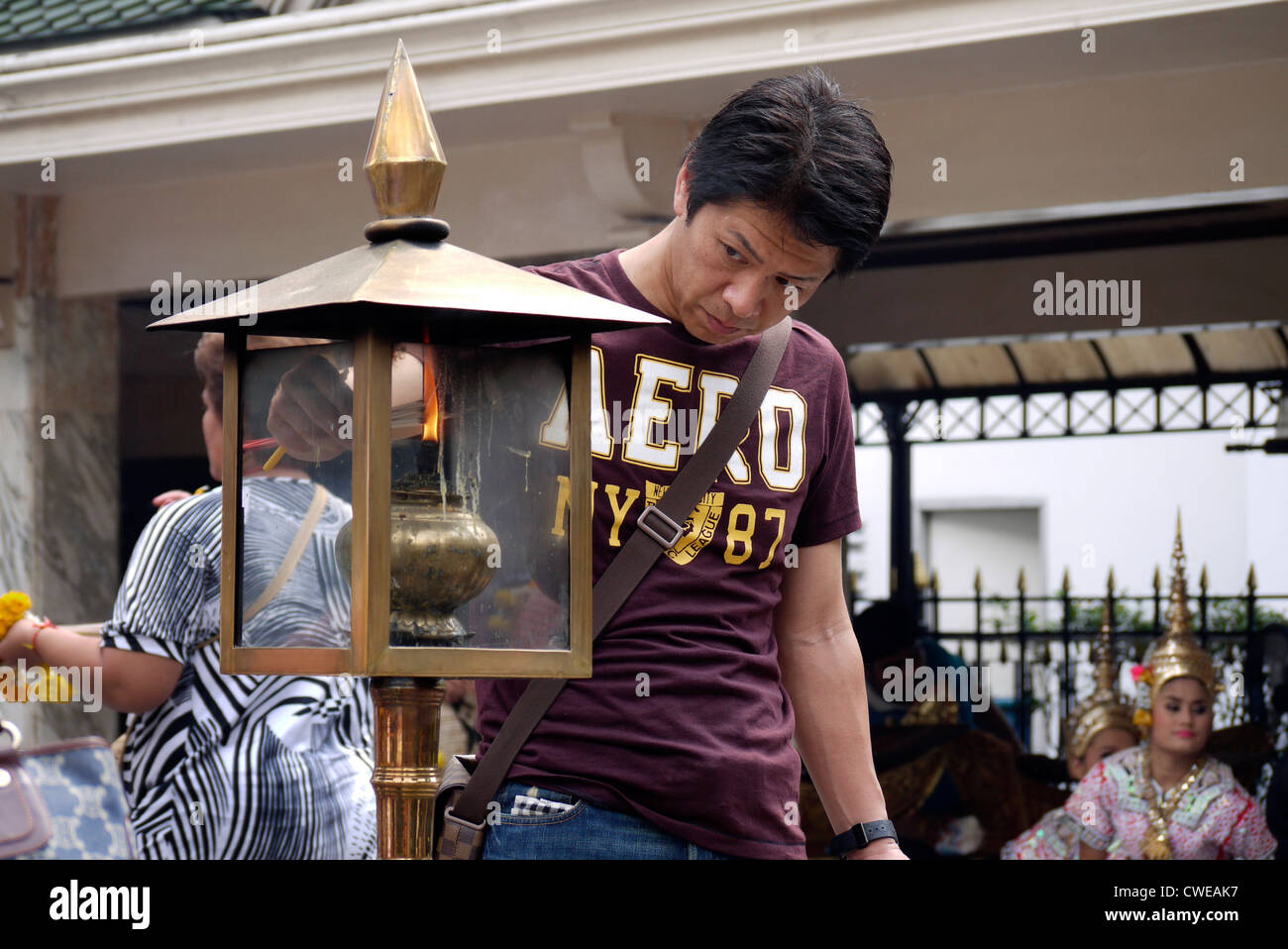Thai maschio bruciando incenso presso il Santuario di Erawan Bangkok in Thailandia Foto Stock
