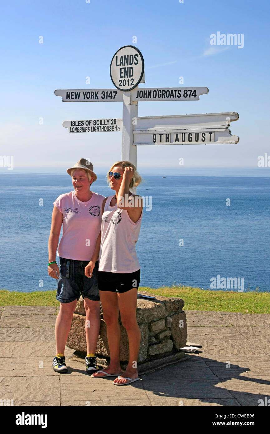 Due donne pongono sotto il famoso Lands End sign in Cornwall Inghilterra Foto Stock