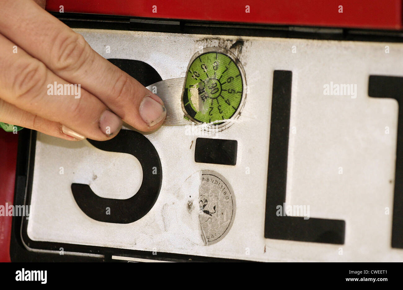 MOT Test - raschiare via il vecchio adesivo di controllo sul veicolo posteriore Foto Stock