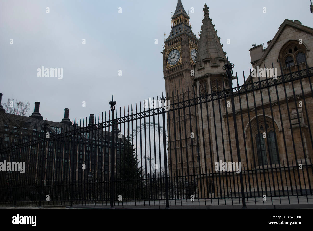 Il Palazzo di Westminster con il Big Ben e Portcullis House dietro ringhiere in ferro con il London Eye in background Foto Stock