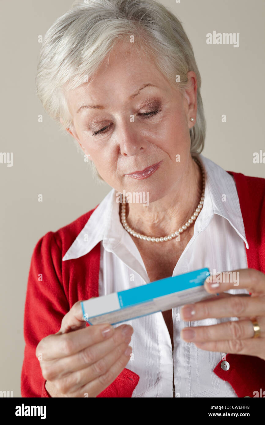 Senior donna che guarda la prescrizione dei farmaci pack Foto Stock