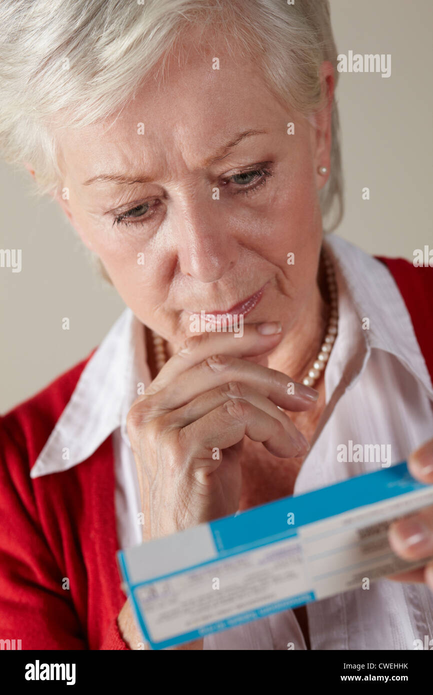 Senior donna che guarda la prescrizione dei farmaci pack Foto Stock