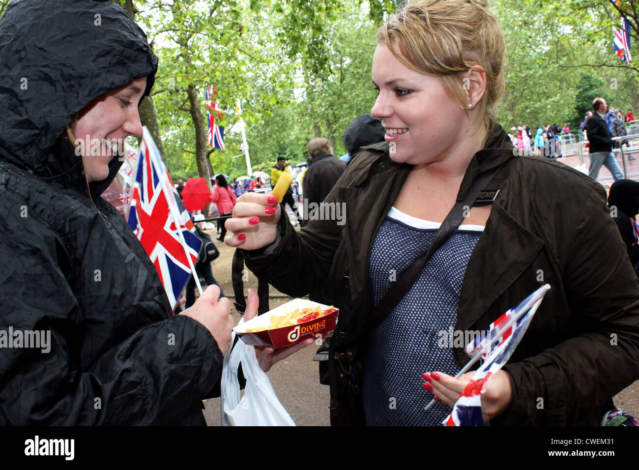 Due giovani donne mangiare pesce e patatine sul Mall. Le celebrazioni nella regina del Giubileo di diamante di Londra, 2012 Foto Stock