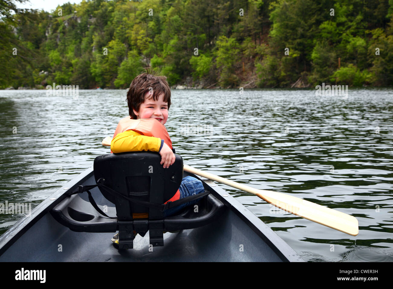 Sorridente ragazzo su una canoa in un lago Foto Stock