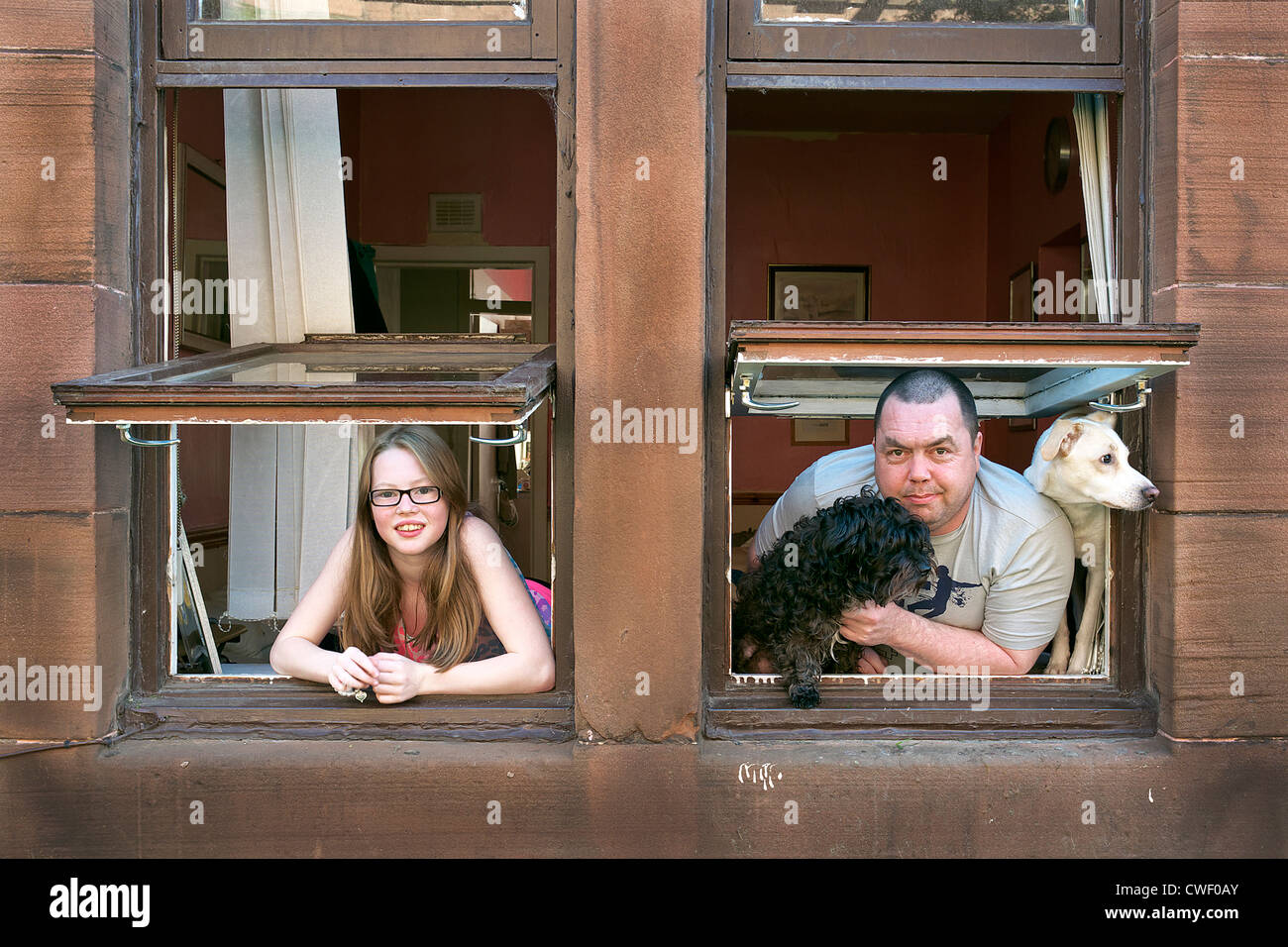 Padre e figlia appoggiata al di fuori di un tenement finestra, Govan, Glasgow Foto Stock