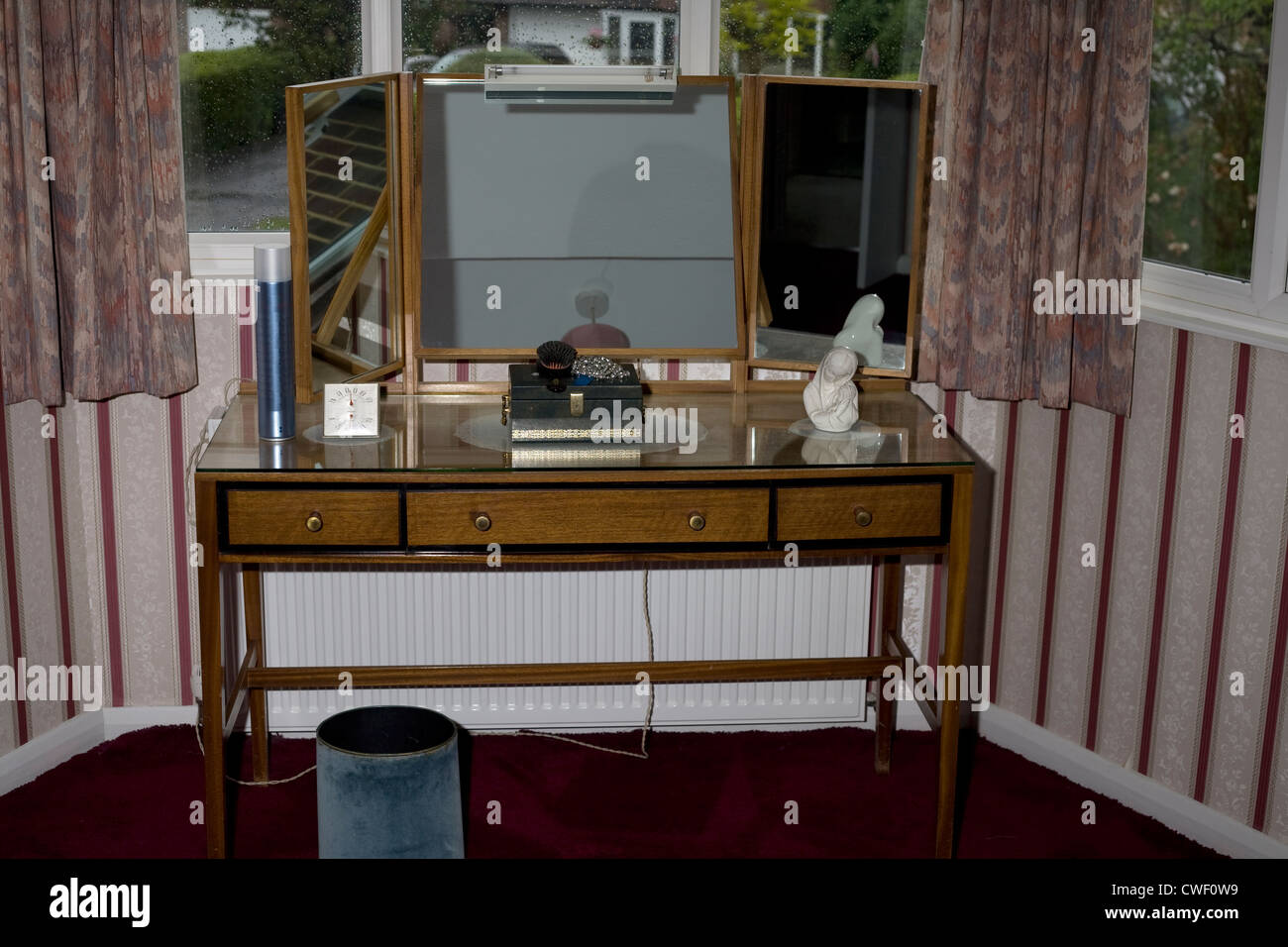 Un tavolino con specchi in una camera da letto da una finestra di baia con una collana caso,termometro, aerosol e statua Foto Stock