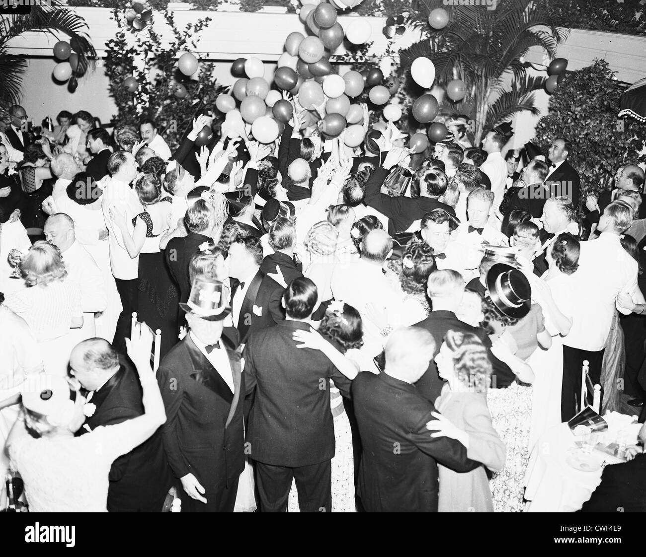 I festaioli cercando di catturare palloncini cadere dal soffitto per la Vigilia di Capodanno al Patio, Palm Beach, Florida, Dicembre 31,1941 Foto Stock