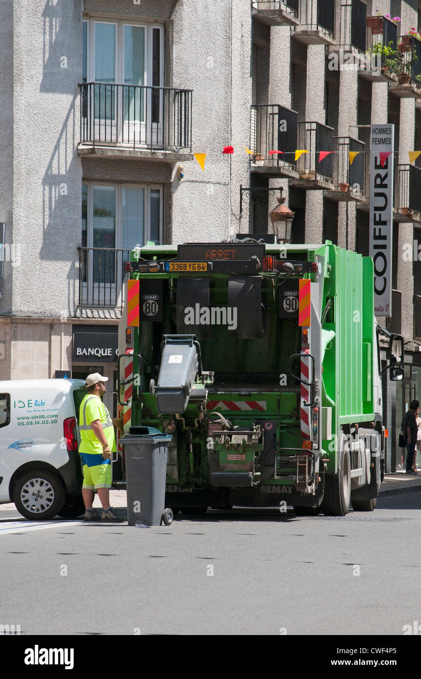 L uomo si svuota wheely bin in un carrello a Pau centro città sud-ovest della Francia Foto Stock