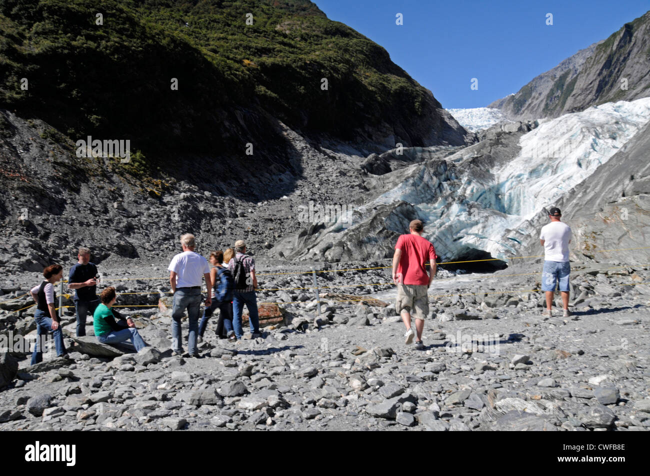 I visitatori si riuniscono per ammirare il ghiacciaio Franz Josef con il suo mix di rocce e ghiaccio che raggiunge il fondo della valle al ghiacciaio lungo 12 km vicino ai 12 km Foto Stock