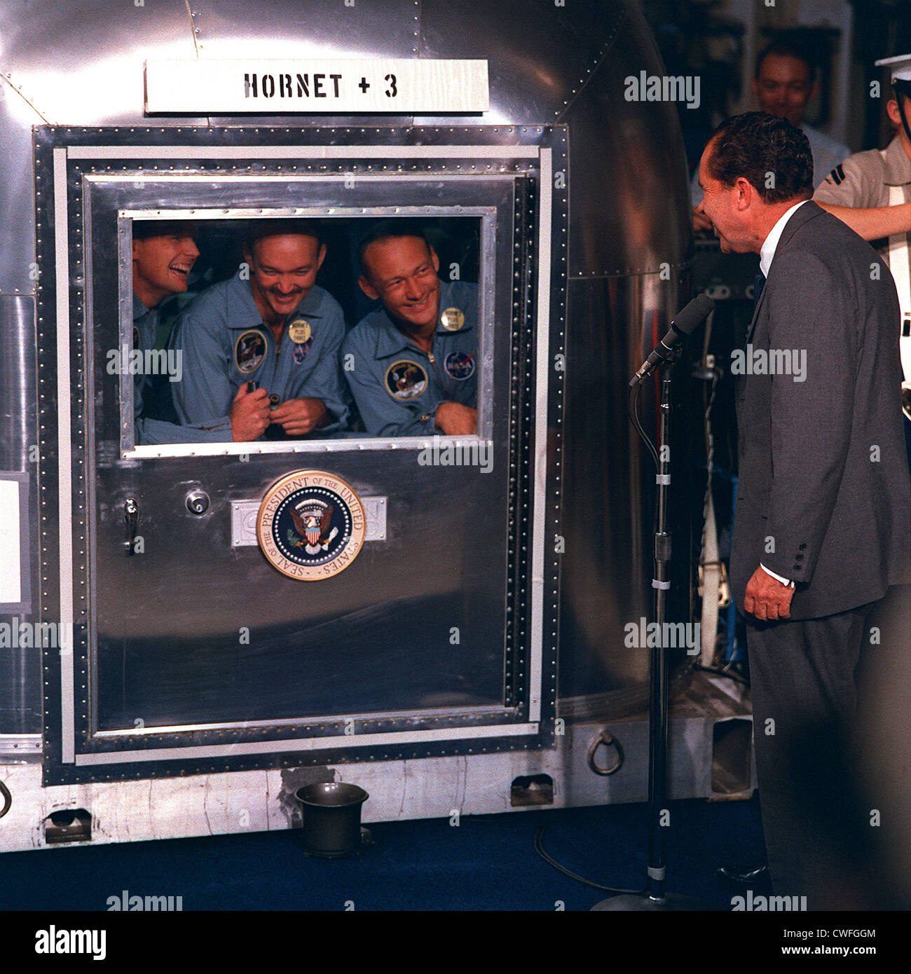 Il presidente statunitense Richard Nixon accoglie con favore l' Apollo 11 home gli astronauti a bordo della USS Hornet dopo il ritorno dal loro storico volo per la luna Luglio 24, 1969 nell'Oceano Pacifico. Gli astronauti confinata al Mobile impianto di quarantena sono (da sinistra a destra) Neil A. Armstrong, comandante; Michael Collins, il pilota del modulo di comando; e Edwin E. Aldrin Jr., modulo lunare pilota. Foto Stock
