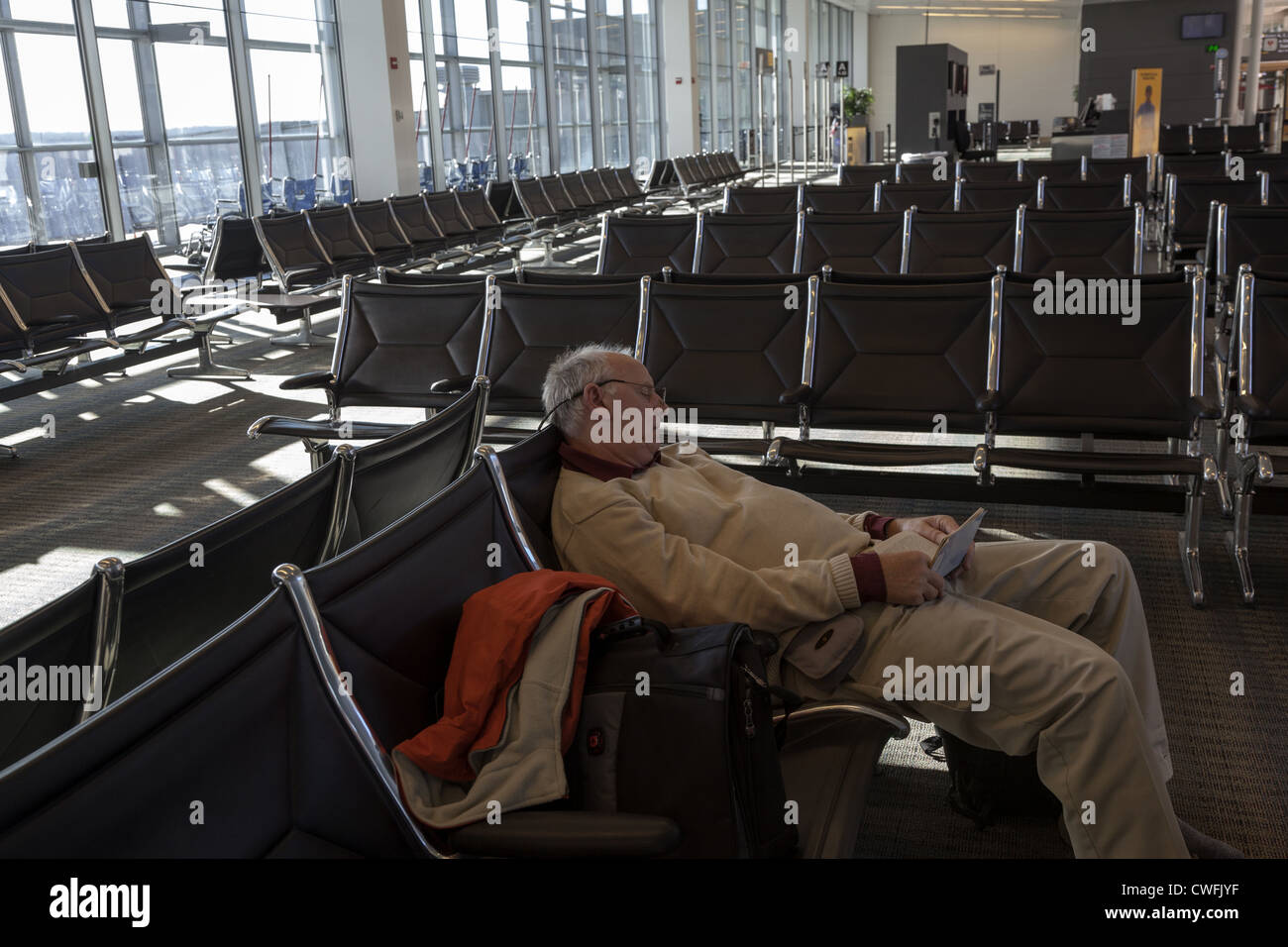 L'uomo addormentato in vuoto area con posti a sedere di partenza lounge all'aeroporto Dulles Washington DC USA Foto Stock