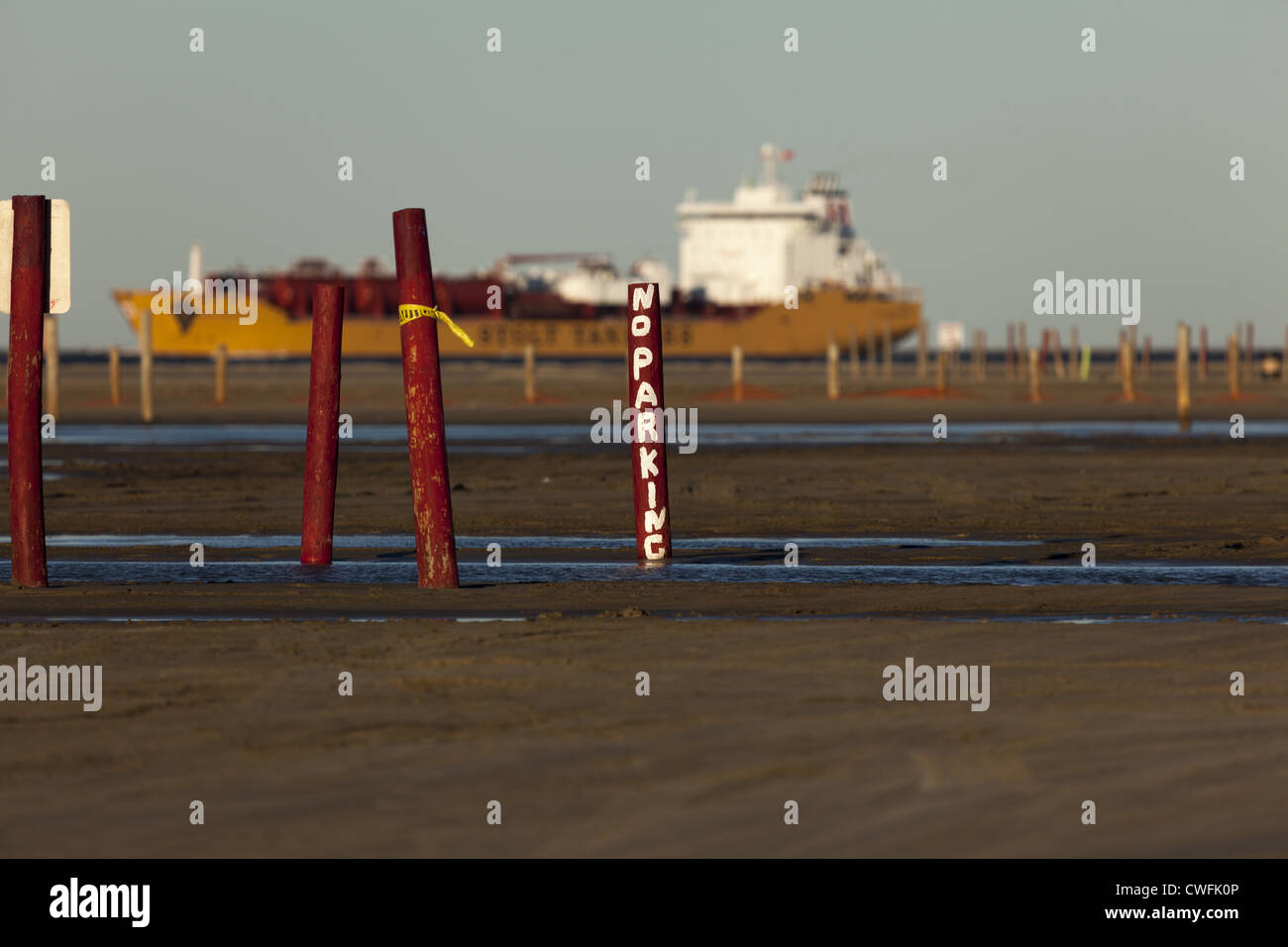 Nessun segno di parcheggio dipinto a mano in pole con la nave da carico in background che sembra essere parcheggiato a East Beach, Galveston, Texas Foto Stock